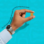 Hand holding a yellow supplement capsule with text on a blue background