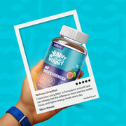 Hand holding a bottle of 'Yummy Gummy' Men's Formula with a blue background